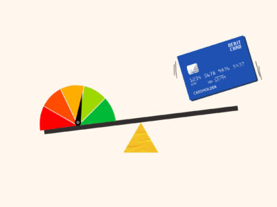 Debit card dropping onto seesaw holding credit score gauge