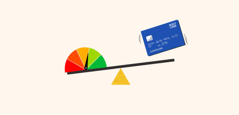 Debit card dropping onto seesaw holding credit score gauge